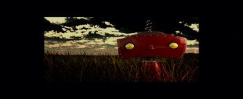 Movie still from “The Cloverfield Paradox” (2018), directed by Julius Onah – A red fire hydrant sitting in the middle of a grassy field; Extreme Close Up shot, Overhead angle