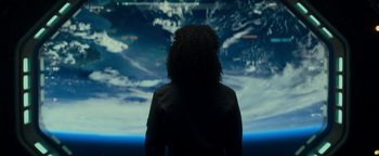 Movie still from “The Cloverfield Paradox” (2018), directed by Julius Onah – A woman standing in front of a large screen; Medium shot, Low angle