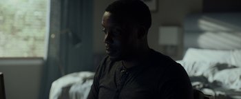 Movie still from “The Cloverfield Paradox” (2018), directed by Julius Onah – A man sitting in a dark room looking off into the distance; Close Up shot, Over the shoulder angle
