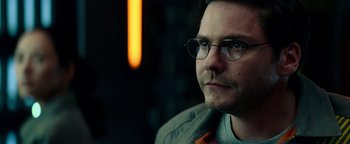 Movie still from “The Cloverfield Paradox” (2018), directed by Julius Onah – A person wearing glasses and a jacket; Close Up shot, Over the shoulder angle