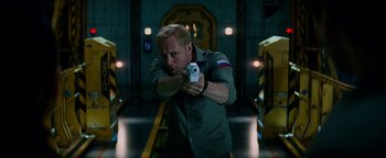 Movie still from “The Cloverfield Paradox” (2018), directed by Julius Onah – A man holding a gun while standing in a room; Medium shot, Low angle