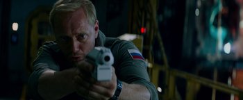 Movie still from “The Cloverfield Paradox” (2018), directed by Julius Onah – A man holding a gun in his hands; Close Up shot, Low angle