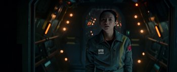 Movie still from “The Cloverfield Paradox” (2018), directed by Julius Onah – A woman standing in front of lights in a room; Medium shot, Over the shoulder angle