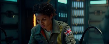 Movie still from “The Cloverfield Paradox” (2018), directed by Julius Onah – A woman with a british flag on her jacket; Close Up shot, Over the shoulder angle