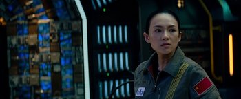 Movie still from “The Cloverfield Paradox” (2018), directed by Julius Onah – A woman standing in front of a wall with lights on it; Close Up shot, Over the shoulder angle