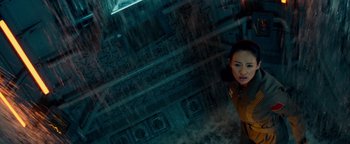 Movie still from “The Cloverfield Paradox” (2018), directed by Julius Onah – A woman standing next to a building in the rain; Medium shot, Overhead angle