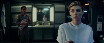 Movie still from “The Cloverfield Paradox” (2018), directed by Julius Onah – A woman standing in front of a mirror in a room; Medium shot, Over the shoulder angle