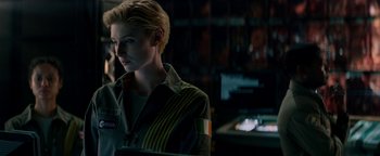 Movie still from “The Cloverfield Paradox” (2018), directed by Julius Onah – A woman with short blonde hair is standing in front of a bookshelf; Close Up shot, Over the shoulder angle