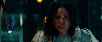 Movie still from “The Cloverfield Paradox” (2018), directed by Julius Onah – A woman with curly black hair is looking at the camera; Close Up shot, Over the shoulder angle