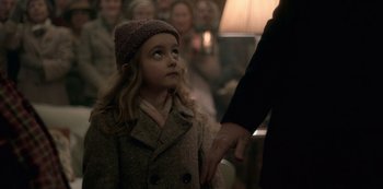 Movie still from “The Crown” (2016), created by Peter Morgan – A little girl wearing a coat and a hat looking up at an adult; Close Up shot, Over the shoulder angle