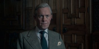 Movie still from “The Crown” (2016), created by Peter Morgan – An older man wearing a suit and tie; Close Up shot, Over the shoulder angle