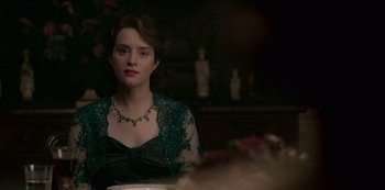 Movie still from “The Crown” (2016), created by Peter Morgan – A woman sitting at a table in front of a plate of food; Close Up shot, Over the shoulder angle