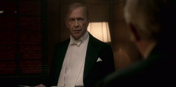 Movie still from “The Crown” (2016), created by Peter Morgan – An older man in a tuxedo looking into a mirror; Medium shot, Over the shoulder angle