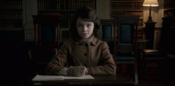 Movie still from “The Crown” (2016), created by Peter Morgan – A girl sitting at a table writing on a piece of paper; Medium shot, High angle