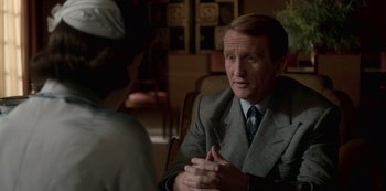 Movie still from “The Crown” (2016), created by Peter Morgan – A man in a suit and tie talking to a woman; Close Up shot, Over the shoulder angle