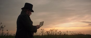 Movie still from “Mr. Turner” (2014), directed by Mike Leigh – A man holding a book while standing in a field; Medium shot, Low angle