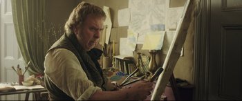 Movie still from “Mr. Turner” (2014), directed by Mike Leigh – An older man is painting in a room; Medium shot, Over the shoulder angle
