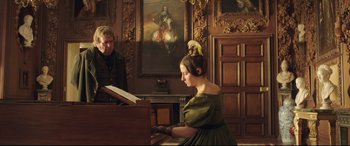 Movie still from “Mr. Turner” (2014), directed by Mike Leigh – A woman sitting at a piano in front of a painting; Medium shot, Over the shoulder angle