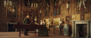 Movie still from “Mr. Turner” (2014), directed by Mike Leigh – A man and a woman are sitting at a piano in front of statues of busts; Wide shot, Low angle