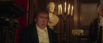 Movie still from “Mr. Turner” (2014), directed by Mike Leigh – A man standing in front of a statue with candles; Medium shot, Over the shoulder angle