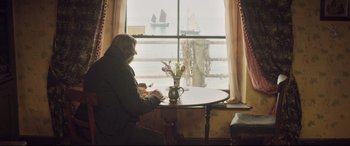 Movie still from “Mr. Turner” (2014), directed by Mike Leigh – An older man sitting at a table looking out a window at a sailboat; Wide shot, Over the shoulder angle