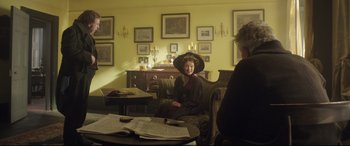 Movie still from “Mr. Turner” (2014), directed by Mike Leigh – A woman sitting on a couch in a living room; Wide shot, Over the shoulder angle