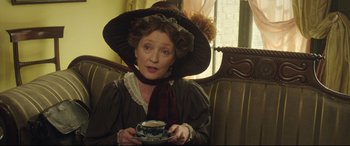 Movie still from “Mr. Turner” (2014), directed by Mike Leigh – An older woman wearing a hat and holding a cup; Medium shot, High angle