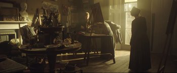 Movie still from “Mr. Turner” (2014), directed by Mike Leigh – A person sitting at a table in front of an easel in a room; Wide shot, Low angle