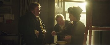 Movie still from “Mr. Turner” (2014), directed by Mike Leigh – A group of people standing in a room with a bowl; Medium shot, Over the shoulder angle