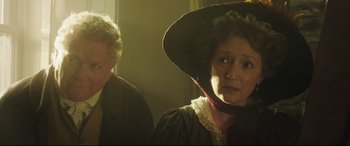 Movie still from “Mr. Turner” (2014), directed by Mike Leigh – A woman wearing a large hat and a man wearing a large hat; Medium shot, Over the shoulder angle