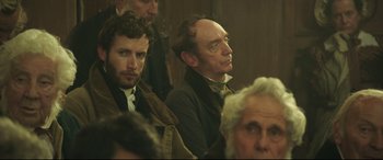 Movie still from “Mr. Turner” (2014), directed by Mike Leigh – Two men sitting next to each other in front of a crowd; Close Up shot, Over the shoulder angle