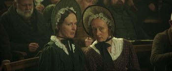 Movie still from “Mr. Turner” (2014), directed by Mike Leigh – A couple of women wearing hats and standing next to each other; Medium shot, High angle