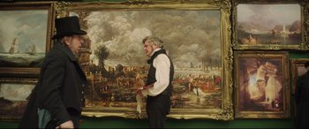 Movie still from “Mr. Turner” (2014), directed by Mike Leigh – A man standing in front of a large painting; Medium shot, Over the shoulder angle