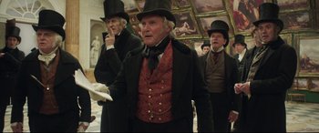 Movie still from “Mr. Turner” (2014), directed by Mike Leigh – A group of men in top hats and coats; Medium shot, Low angle