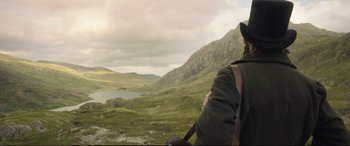 Movie still from “Mr. Turner” (2014), directed by Mike Leigh – A person with a backpack and hat looking out at a lake; Wide shot, Over the shoulder angle