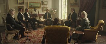 Movie still from “Mr. Turner” (2014), directed by Mike Leigh – A group of people sitting in a living room; Wide shot, Over the shoulder angle