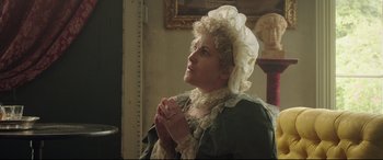 Movie still from “Mr. Turner” (2014), directed by Mike Leigh – An older woman in a period dress praying; Medium shot, Low angle