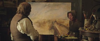 Movie still from “Mr. Turner” (2014), directed by Mike Leigh – Two people are painting in front of a large painting; Medium shot, Over the shoulder angle