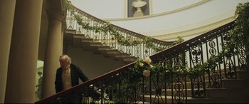 Movie still from “Mr. Turner” (2014), directed by Mike Leigh – A man walking down a staircase with flowers on the railing; Wide shot, Low angle