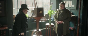 Movie still from “Mr. Turner” (2014), directed by Mike Leigh – Two men standing in front of a plant in front of a window; Medium shot, Over the shoulder angle