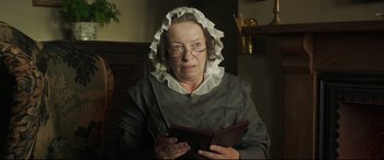 Movie still from “Mr. Turner” (2014), directed by Mike Leigh – An older woman wearing a hat and reading a book; Close Up shot, Low angle