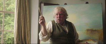 Movie still from “Mr. Turner” (2014), directed by Mike Leigh – A man holding a paintbrush in front of an easel; Close Up shot, Low angle
