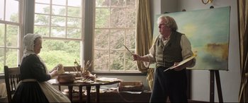 Movie still from “Mr. Turner” (2014), directed by Mike Leigh – An older man holding a paintbrush in front of an easel; Medium shot, Low angle