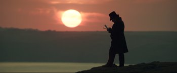 Movie still from “Mr. Turner” (2014), directed by Mike Leigh – A person standing on top of a hill looking at a cell phone; Wide shot, Low angle