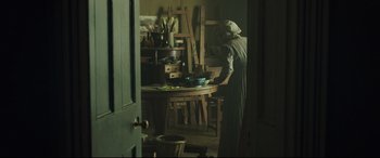 Movie still from “Mr. Turner” (2014), directed by Mike Leigh – An old woman standing in front of a table in a room; Wide shot, High angle