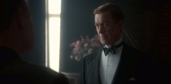 Movie still from “The Crown” (2016), created by Peter Morgan – A person wearing a suit and a bow tie; Close Up shot, Over the shoulder angle