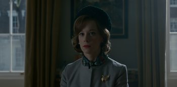 Movie still from “The Crown” (2016), created by Peter Morgan – A woman wearing a green hat and a gray jacket; Close Up shot, Low angle
