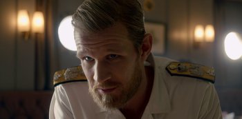 Movie still from “The Crown” (2016), created by Peter Morgan – A person with a beard wearing a uniform; Close Up shot, Over the shoulder angle