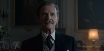 Movie still from “The Crown” (2016), created by Peter Morgan – An older man wearing a suit and tie; Close Up shot, Low angle