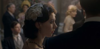 Movie still from “The Crown” (2016), created by Peter Morgan – A person wearing a hat; Close Up shot, Over the shoulder angle